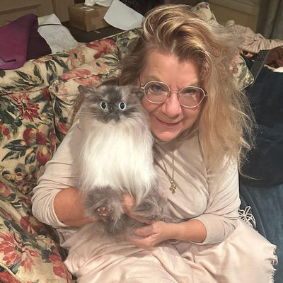Customer resting with the custom stuffed animal of her long-haired cream cat
