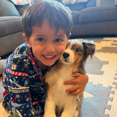 Boy hugging the custom stuffed animal of his tan and white dog