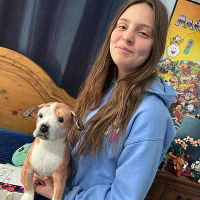 Teenager holding a custom stuffed animal replica of his brown and white dog