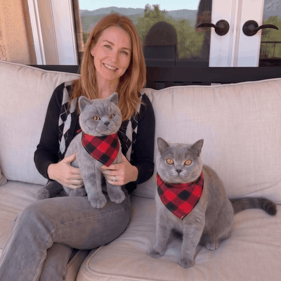 Customer on a sofa with two custom stuffed animals of her grey cats