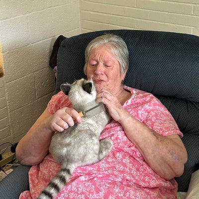 Customer cuddling a stuffed animal replica of her grey and white cat